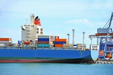 Fototapeta premium Container stack and cargo ship under crane bridge
