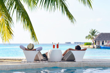 happy young couple relax and take fresh drink on poolside