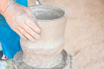 hands of a potter, creating an earthen jar on the circle