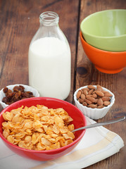 A bowl of cereal with almonds, milk and dried grapes