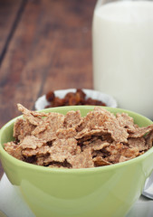 A bowl of cereal with almonds, milk and dried grapes