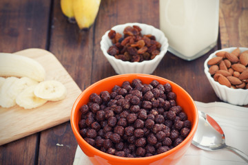 A bowl of cereal with almonds, bananas, milk and dried grapes