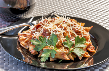 Plate full of Penne A La Vodka with a glass of wine