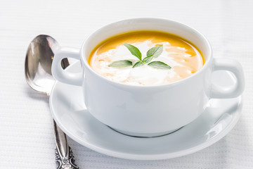 Pumpkin soup with basil on served table