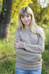 Obraz premium Portrait of young blonde woman in sweater walking in autumn