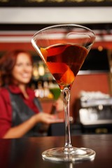 Cheerful barmaid with cocktail behind bar counter
