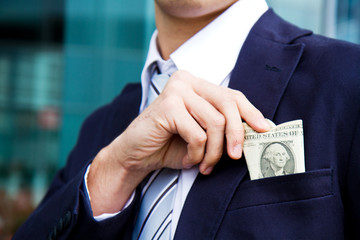businessman outside office taking banknotes