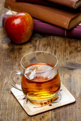 Glass of hot steaming tea on wooden table. Pile of books