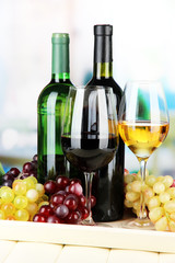 Fototapeta premium Wine bottles and glasses of wine on tray, on bright background