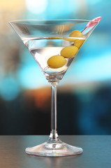 Martini with green olives on table in bar