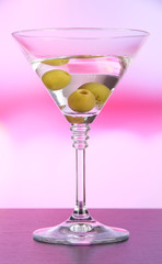 Martini with green olives on table in bar