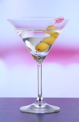 Martini with green olives on table in bar