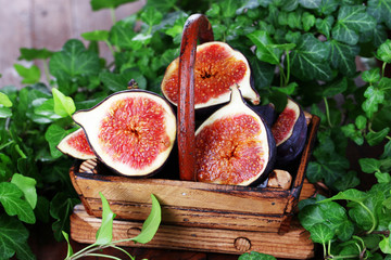 Ripe figs in basket on wooden table close-up