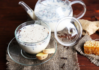 Teapot and cup of tea with milk and spices