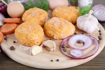 Meat patties on board on wooden table