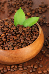 Coffee beans in bowl on wooden background