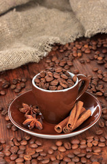 Coffee beans in cup on wooden background