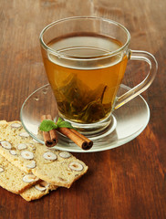Transparent cup of green tea with cookies on wooden background
