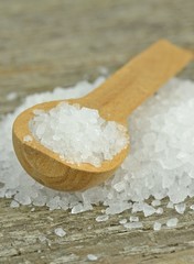 Natural sea salt crystals with wooden spoon on rustic table