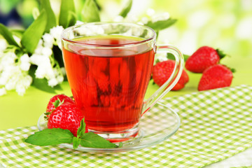 Delicious strawberry tea on table on bright background