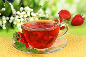 Delicious strawberry tea on table on bright background