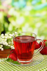 Delicious strawberry tea on table on bright background