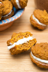 close-up of pumpkin cookies with cream filling on a wooden board