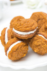 Pumpkin cookies with cream filling on the plate, close-up