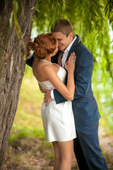 Handsome man snuggling woman to tree