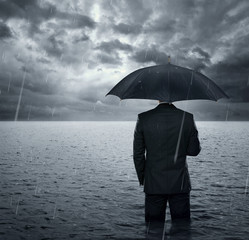 Businessman standing in the dramatic ocean before storm