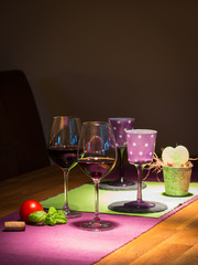 two filled red wine glasses on wooden table with tablecloth
