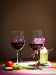 two redwine glasses with tomato and basil on table for couple
