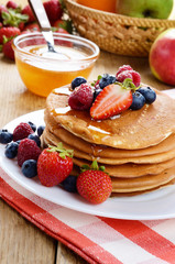 Pancakes with berries and honey closeup