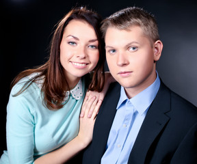 young couple standing together, posing in studio, looking at ca