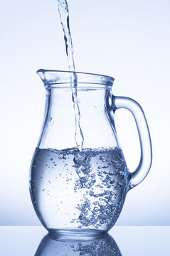 Flowing water in a jug on blue background