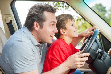Father gives his son driver lessons, enjoying time together