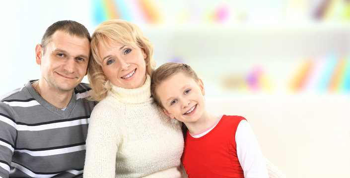 Family With Girl Sitting On White Leather Sofa