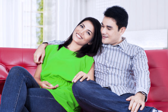 Asian couple relaxing on a red sofa at home