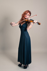 Young woman playing violin portrait. Full body.