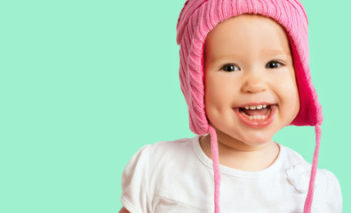 Funny happy baby girl in a pink  winter knitted hat laughing