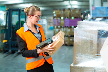 Lageristin von Spedition scannt Paket in einem Lager