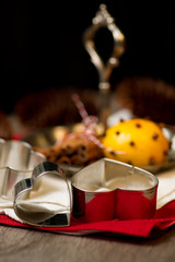 Heart shape gingerbread cutters before cinnamon sticks on silver