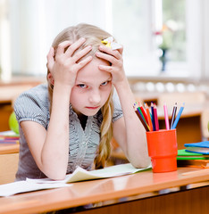 tired schoolgirl in classroom. looking at camera