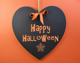 Happy Halloween message written on heart shape blackboard