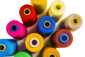 Colored fine thread bobbins on white background