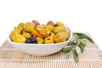 the stuffed olives in a plate with an olive branch lie on a wood