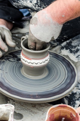 Artist attaching the handle on the cup on pottery from clay