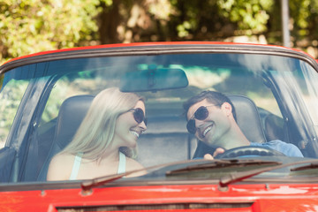 Loving couple in their red cabriolet having a ride