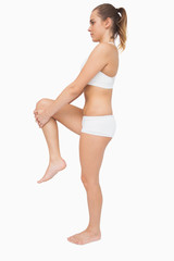 Fototapeta premium Cute ponytailed woman stretching her legs