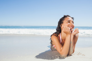 Fototapeta na wymiar Smiling woman lying down on beach